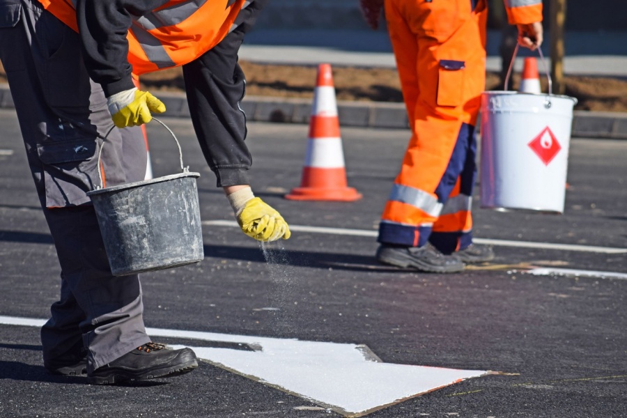 Crew painting a white road marking on fresh asphalt