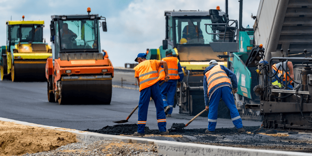 Workers and rollers laying fresh asphalt